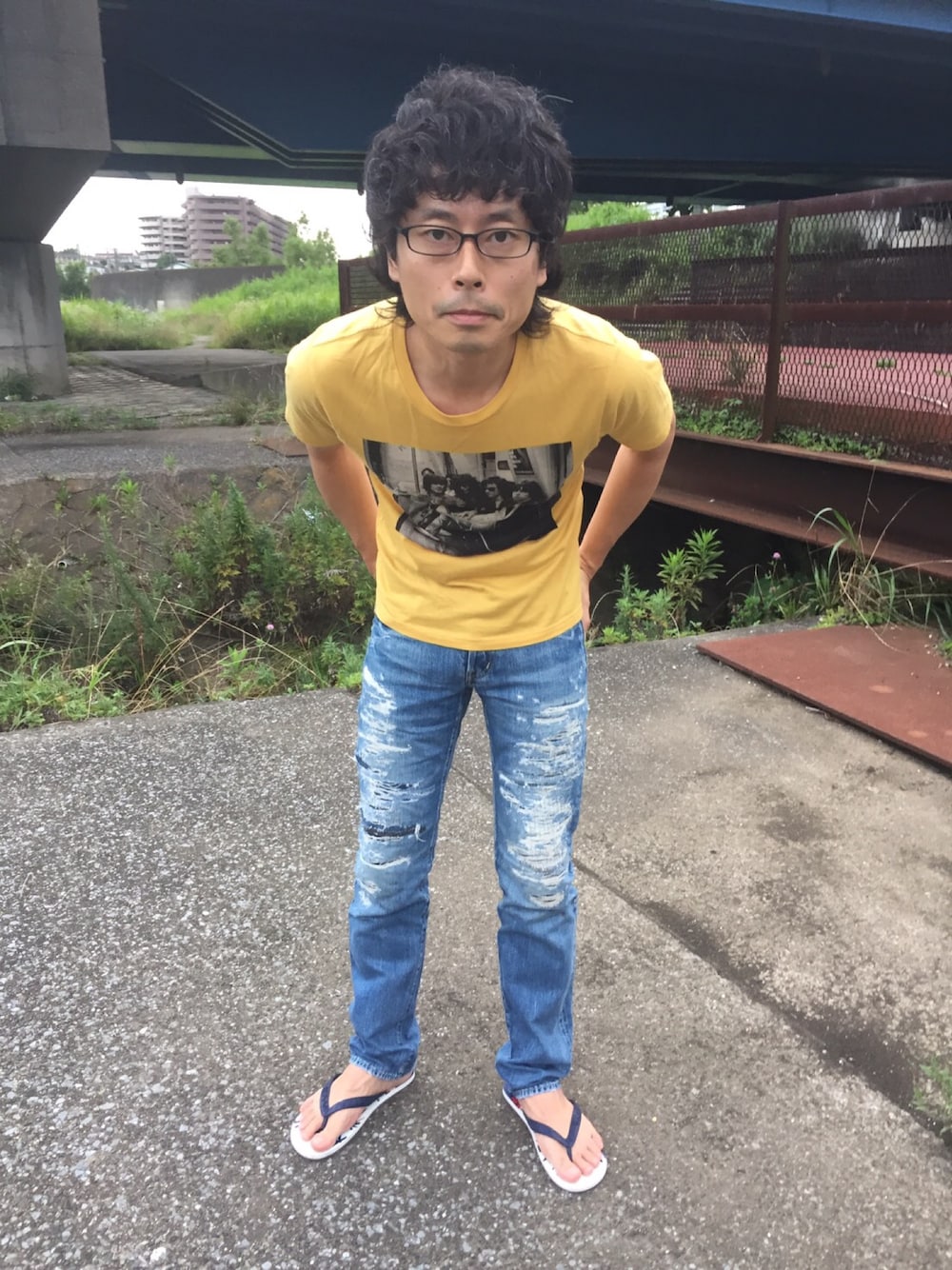 イエロー系のTシャツ/カットソー、ブルー系のデニムパンツ、ブルー系のビーチサンダルを着用したメンズの夏コーディネートの1枚目の写真