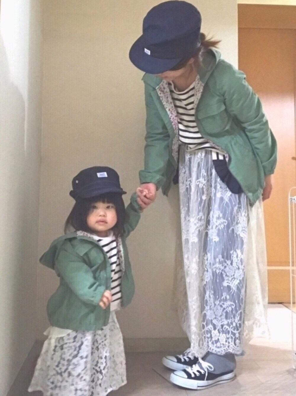 ブラック系のスウェット、グリーン系のミリタリージャケット、ホワイト系のスカートを着用したキッズの春コーディネートの1枚目の写真