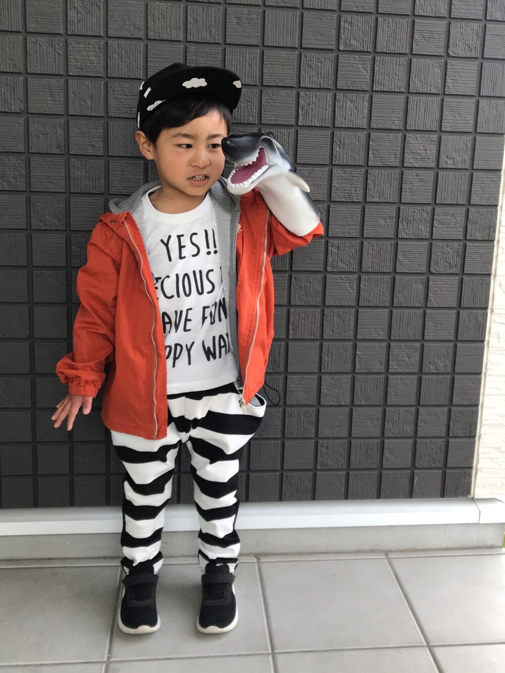 オレンジ系のマウンテンパーカー、グレー系のパーカー、ホワイト系のTシャツ/カットソーを着用したキッズの春コーディネートの1枚目の写真