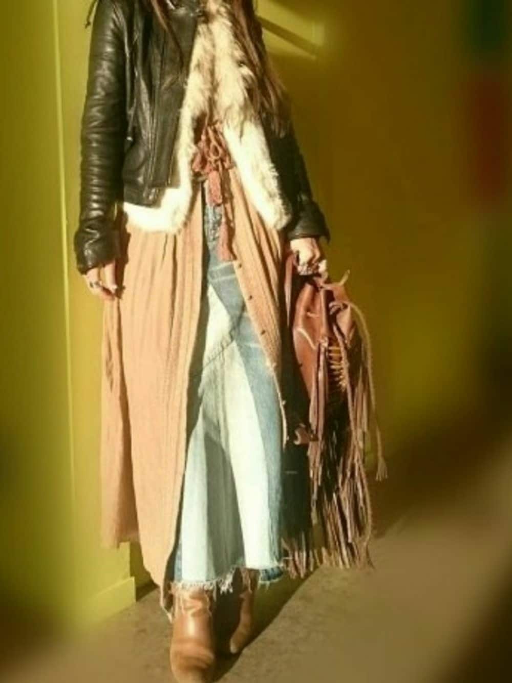 ブラック系のライダースジャケット、オレンジ系のシャツワンピース、ブルー系のデニムスカートを着用したレディースの冬コーディネートの1枚目の写真