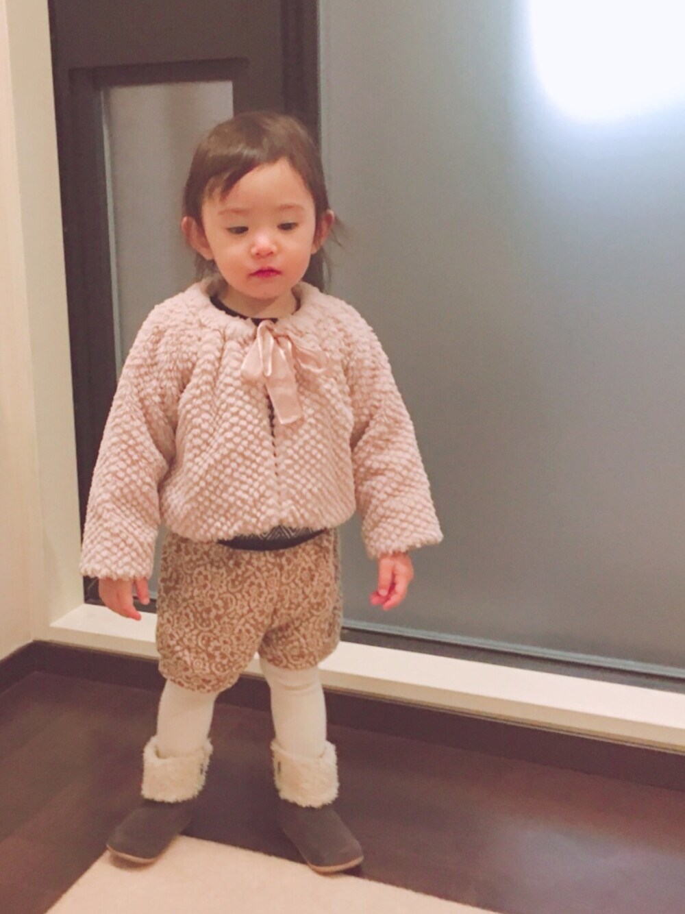 ピンク系のジャケット/アウター、ブラウン系のパンツ、グレー系のブーツを着用したキッズの冬コーディネートの1枚目の写真