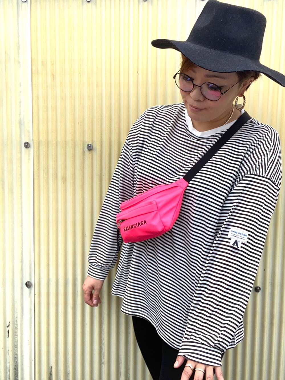 ピンク系のボディバッグ/ウエストポーチ、ブラック系のハット、ブラック系のメガネを着用したレディースの秋コーディネートの1枚目の写真