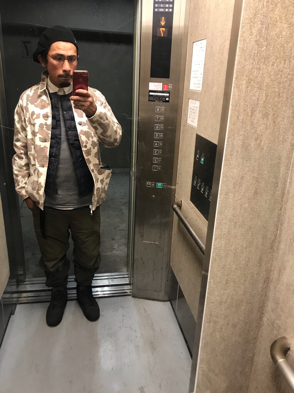 グリーン系のパンツ、ブラック系のスニーカー、ブラウン系のカバーオールを着用したメンズの冬コーディネートの1枚目の写真