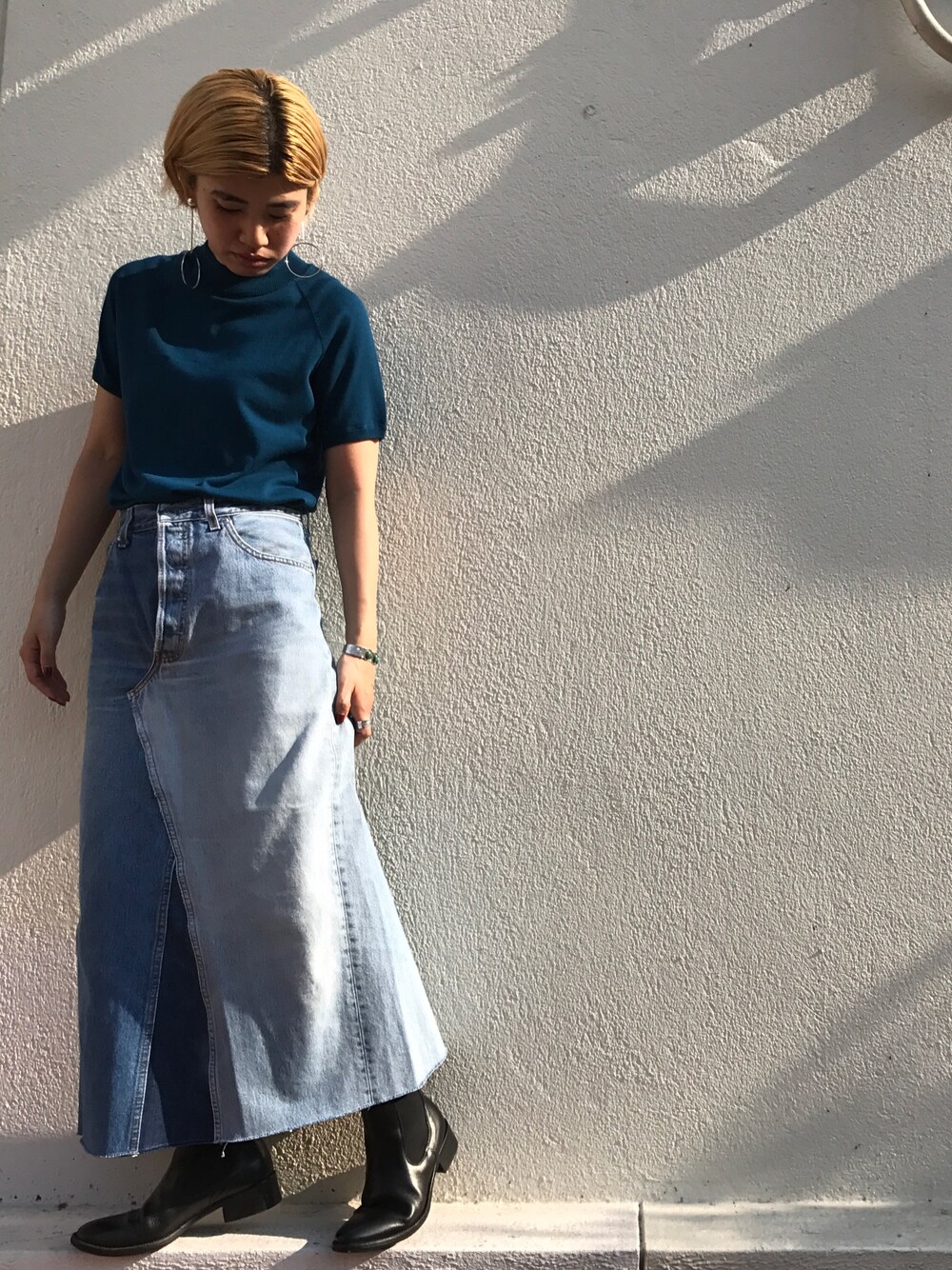 ブルー系のニット/セーター、ブルー系のデニムスカート、シルバー系のイヤリングを着用したレディースの夏コーディネートの1枚目の写真