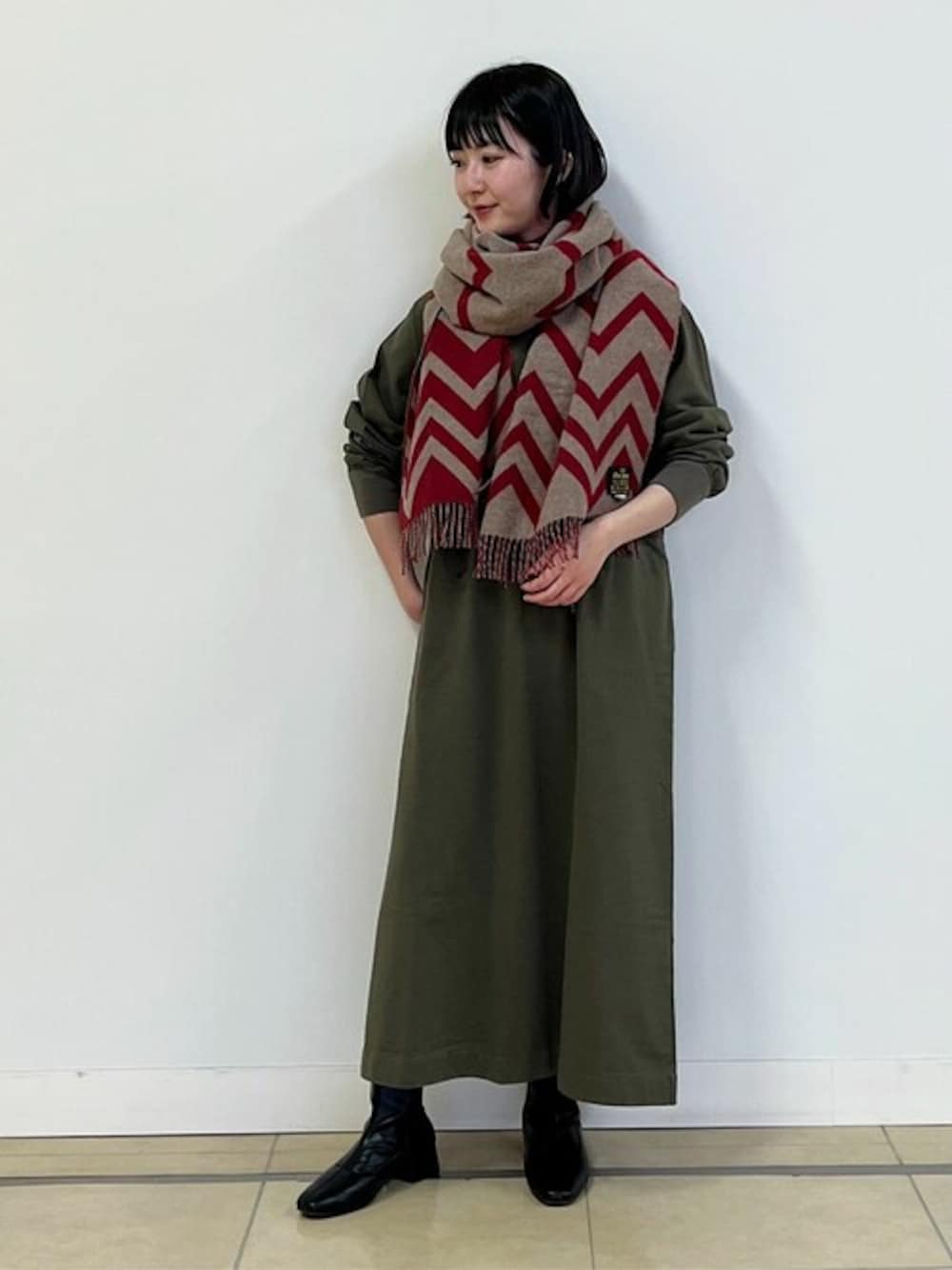 グリーン系のワンピース、レッド系のストール/ショールを着用したレディースの冬コーディネートの1枚目の写真