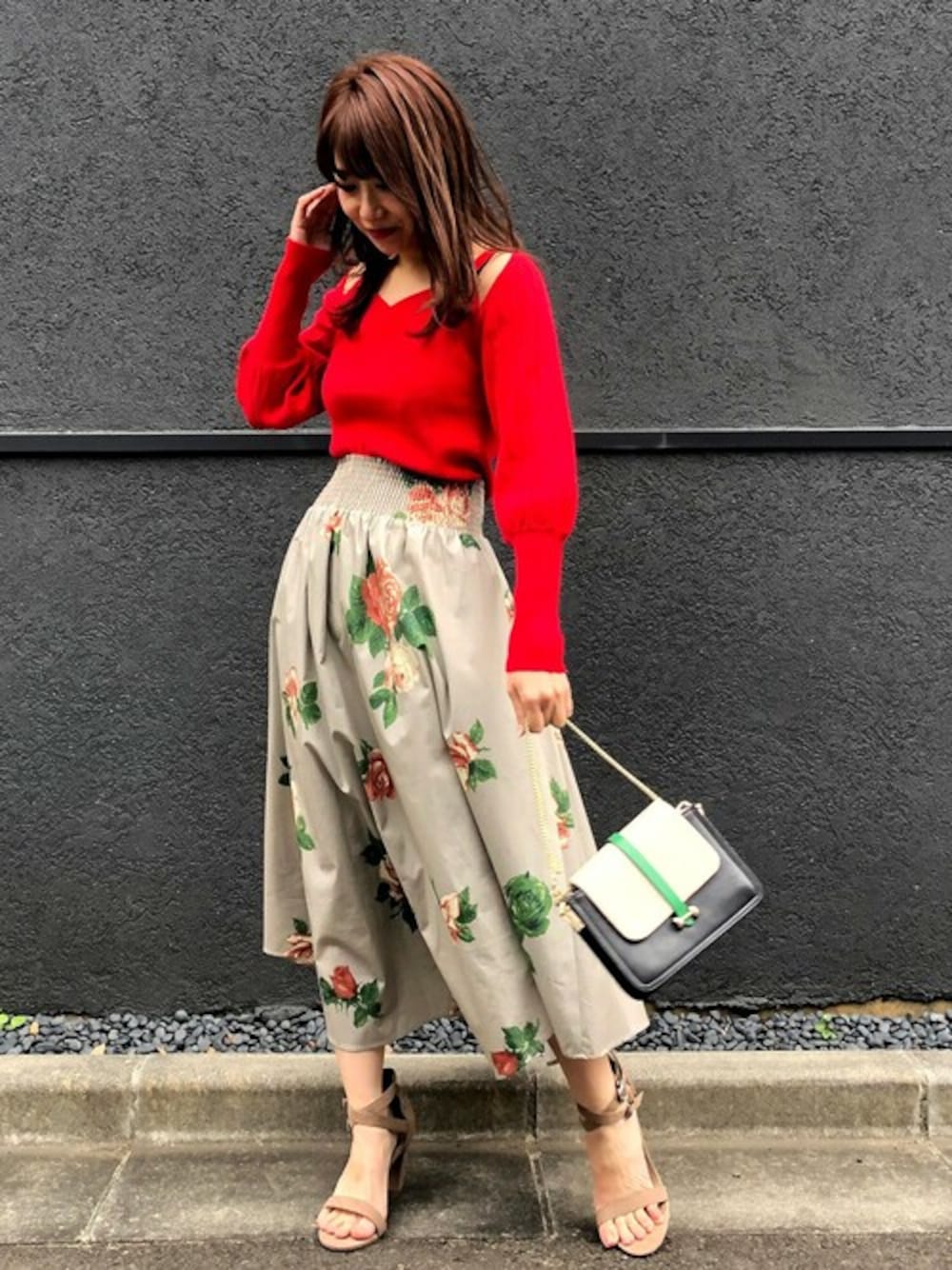 レッド系のニット/セーター、ベージュ系のスカートを着用したレディースの冬コーディネートの1枚目の写真