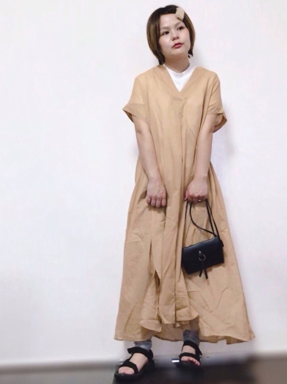 ベージュ系のワンピース、ブラック系のサンダル、ブラック系のショルダーバッグを着用したレディースの春コーディネートの1枚目の写真