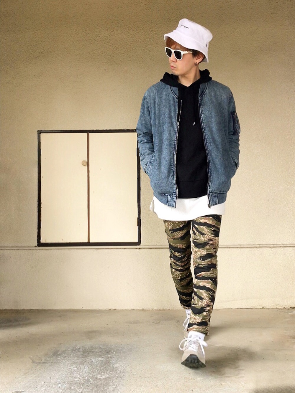 ブルー系のミリタリージャケット、ブラック系のパーカー、その他のチノパンツを着用したメンズの春コーディネートの1枚目の写真