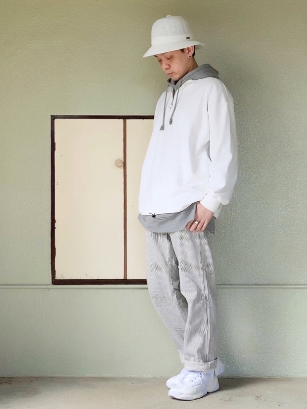 ホワイト系のスニーカー、ホワイト系のパンツ、グレー系のパーカーを着用したメンズの春コーディネートの1枚目の写真