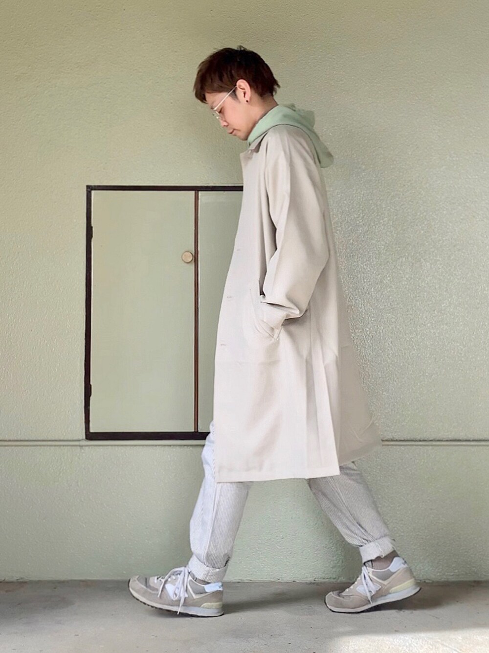 グレー系のスニーカー、ホワイト系のパンツ、グリーン系のパーカーを着用したメンズの冬コーディネートの1枚目の写真