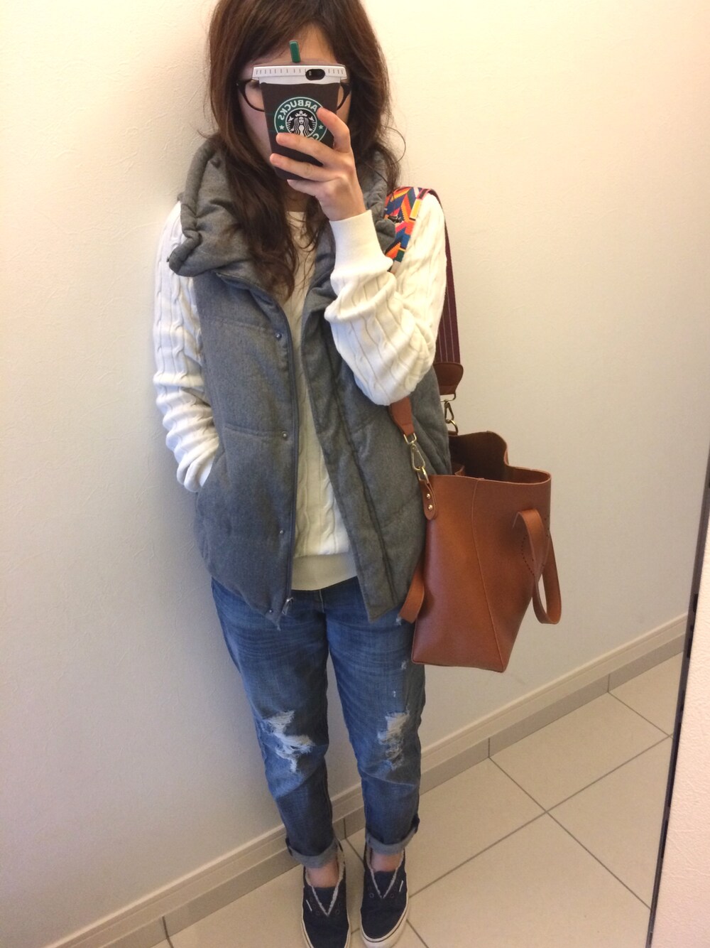 ホワイト系のニット/セーター、グレー系のダウンベスト、ブラウン系のトートバッグを着用したレディースの春コーディネートの1枚目の写真