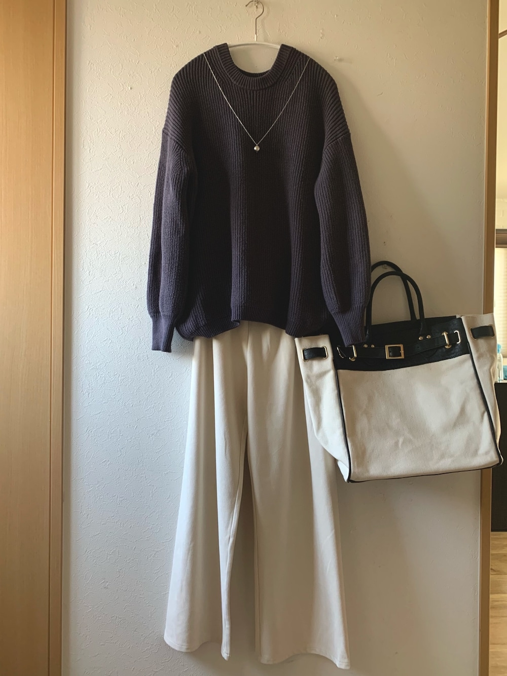 ブルー系のニット/セーター、ホワイト系のパンツ、ブラック系のトートバッグを着用したレディースの冬コーディネートの1枚目の写真