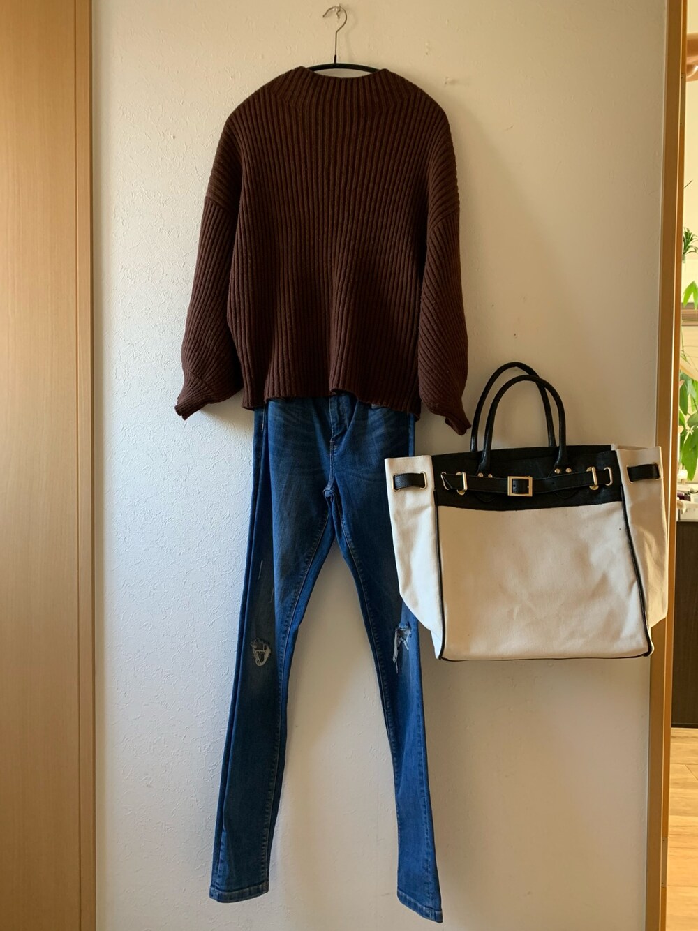 ブラウン系のニット/セーター、ブルー系のデニムパンツ、ブラック系のトートバッグを着用したレディースの冬コーディネートの1枚目の写真