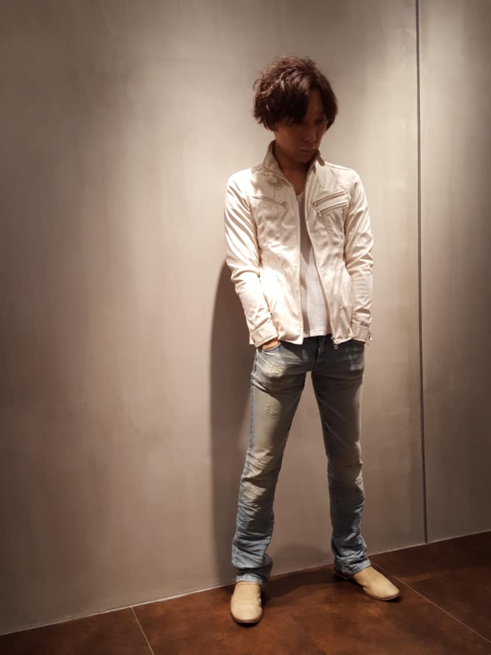 ホワイト系のライダースジャケット、ベージュ系のスリッポンを着用したメンズの春コーディネートの1枚目の写真