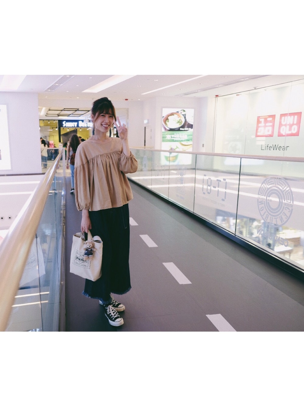 ベージュ系のシャツ/ブラウス、ブルー系のデニムパンツ、ブラック系のスニーカーを着用したレディースの秋コーディネートの1枚目の写真