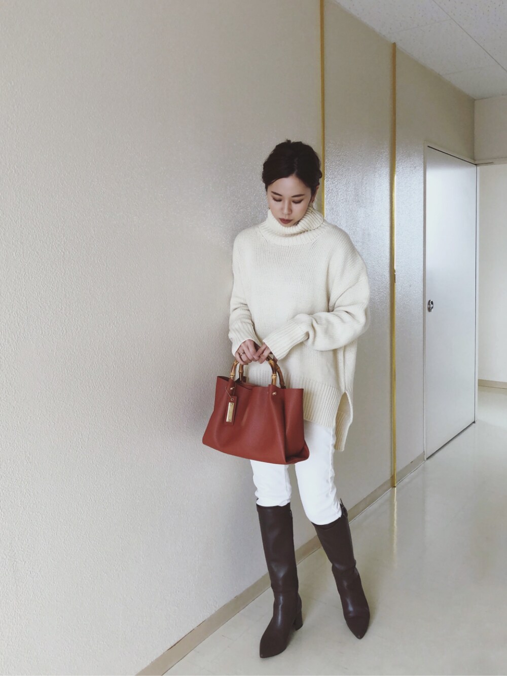 ベージュ系のニット/セーター、ブラウン系のトートバッグ、グリーン系のブーツを着用したレディースの冬コーディネートの1枚目の写真