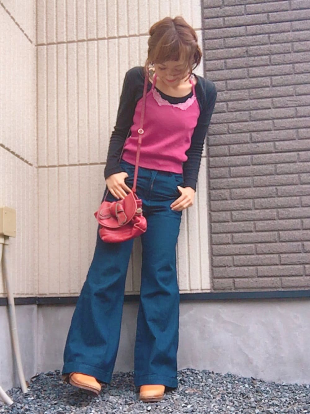 レッド系のショルダーバッグ、ブルー系のデニムパンツ、ブラック系のTシャツ/カットソーを着用したレディースの秋コーディネートの1枚目の写真