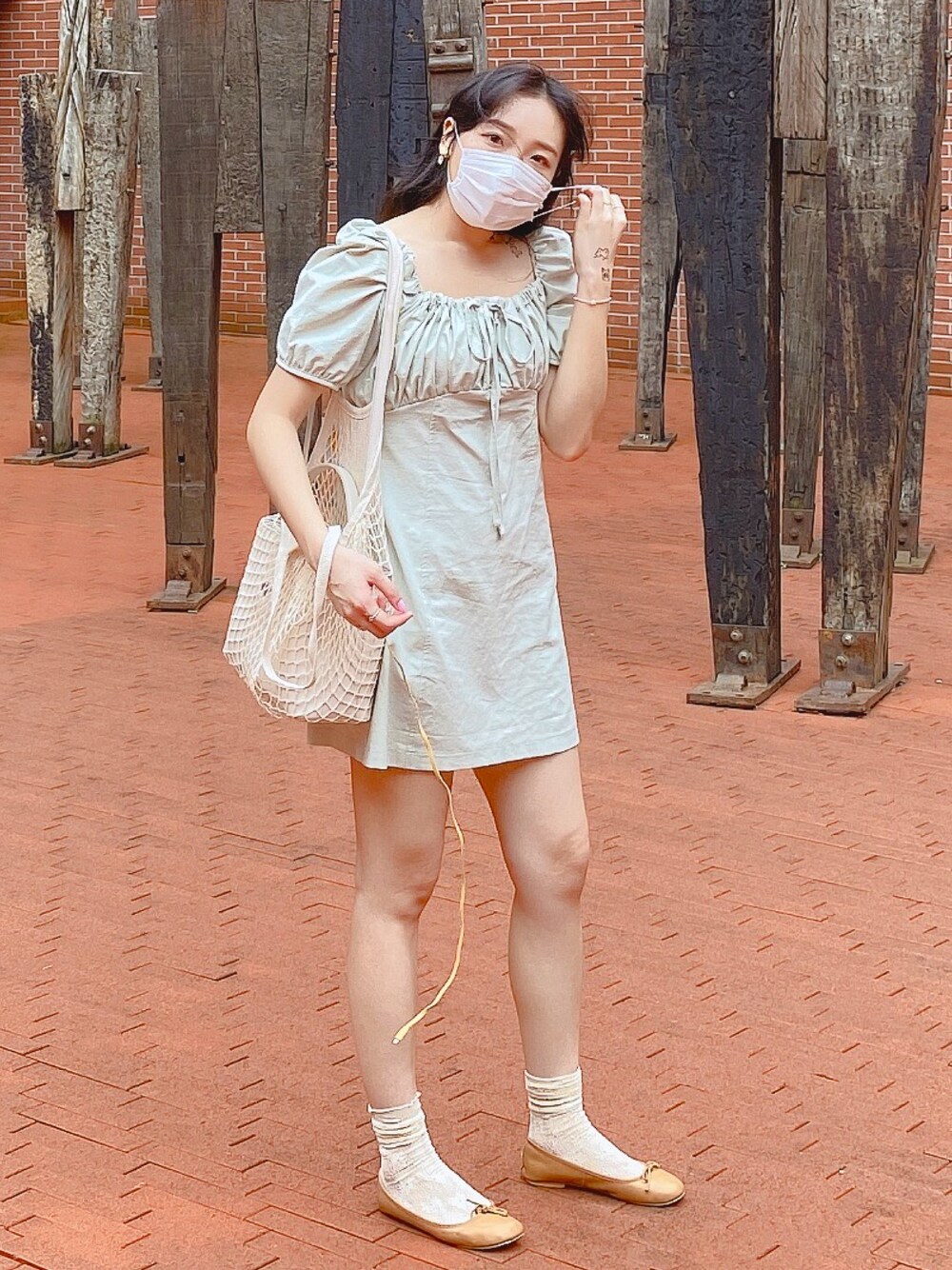 グリーン系のワンピース、ベージュ系のバッグ、ブラウン系のビーチサンダルを着用したレディースの夏コーディネートの1枚目の写真