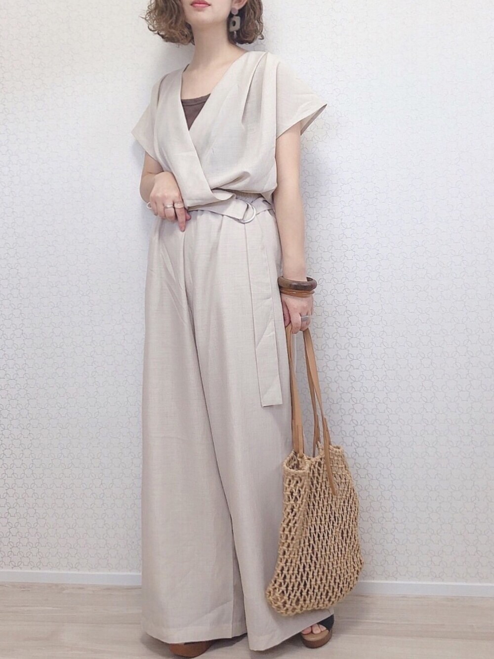 ホワイト系のサロペット/オーバーオール、ベージュ系のトートバッグ、ブラック系のサンダルを着用したレディースの春コーディネートの1枚目の写真