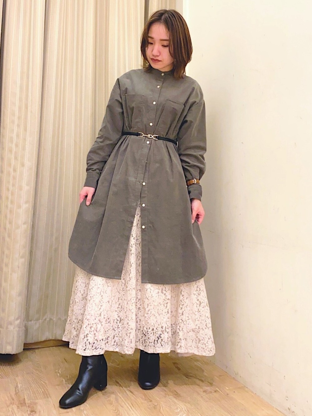 グリーン系のワンピース、ホワイト系のスカート、ブラック系のブーツを着用したレディースの秋コーディネートの1枚目の写真