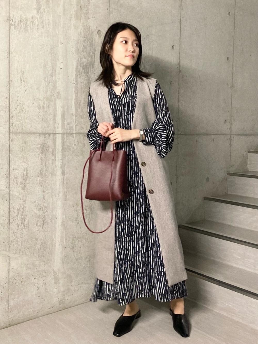 ベージュ系のその他アウター、レッド系のショルダーバッグ、ブラック系のブーツを着用したレディースの夏コーディネートの1枚目の写真