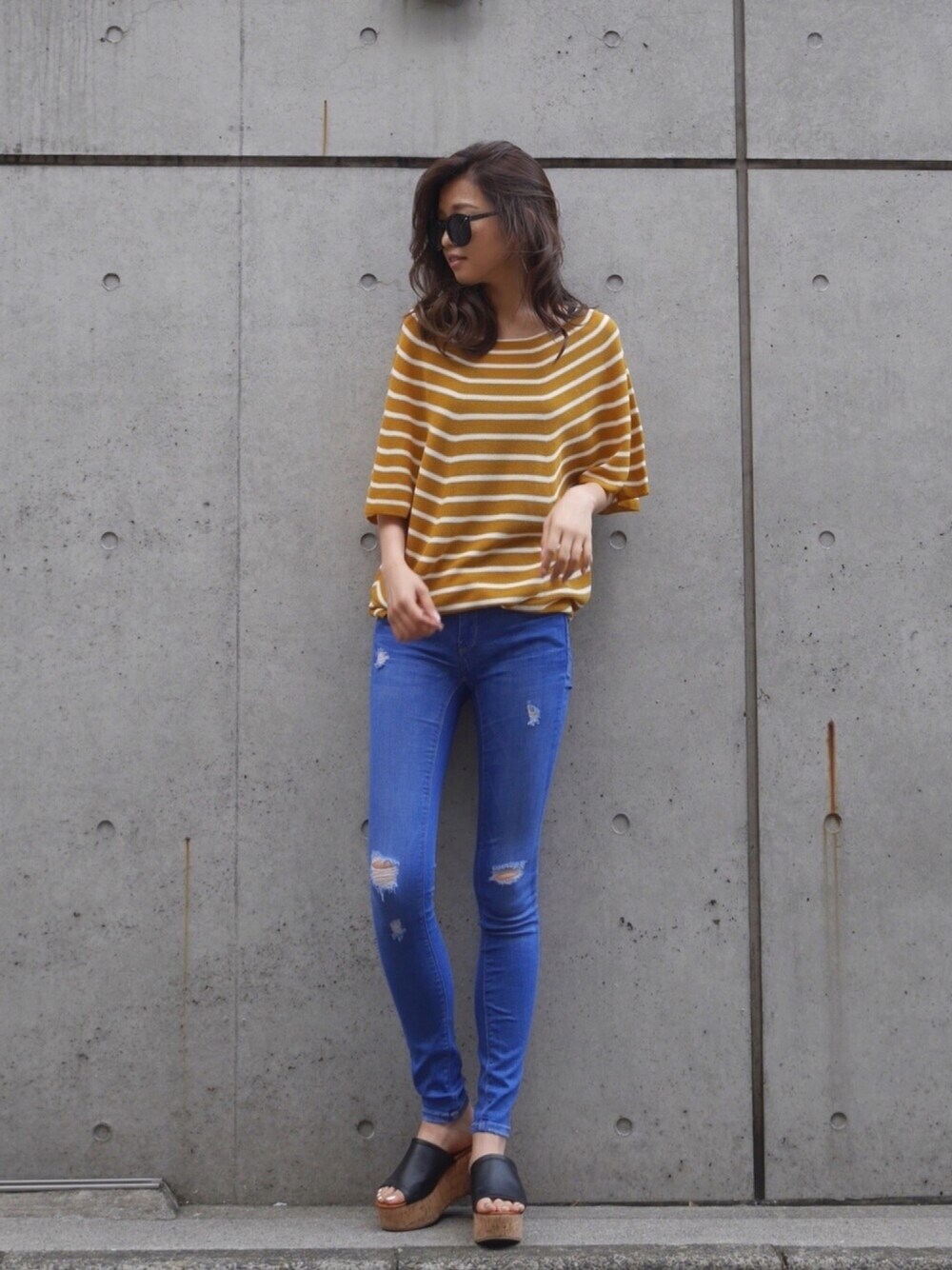 イエロー系のニット/セーター、ブルー系のデニムパンツ、ブラック系のサンダルを着用したレディースの夏コーディネートの1枚目の写真