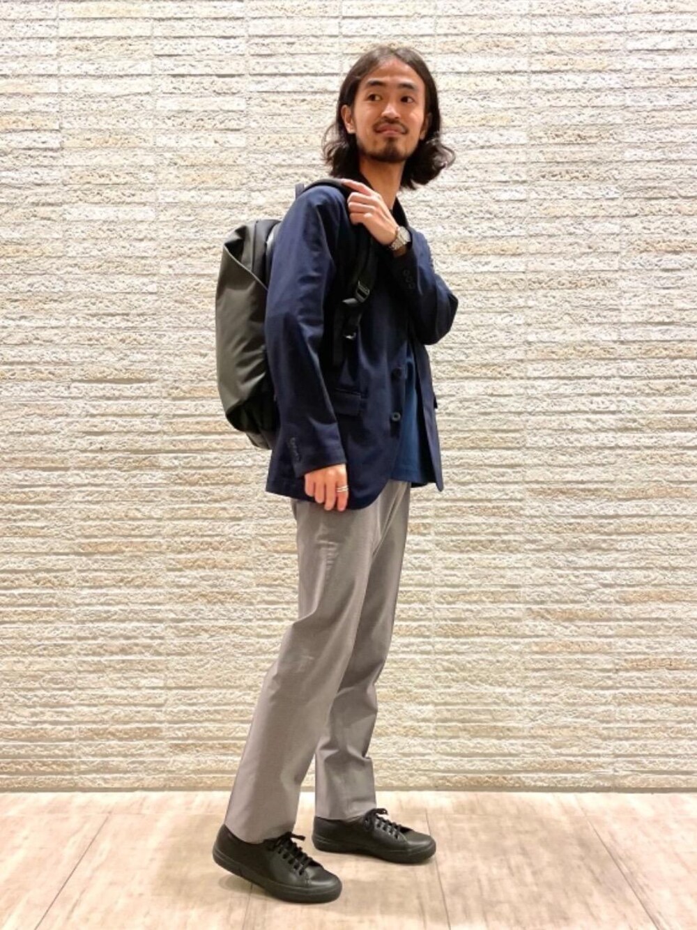 ブラック系のスニーカー、ブルー系のTシャツ/カットソー、グレー系のスラックスを着用したメンズの夏コーディネートの1枚目の写真