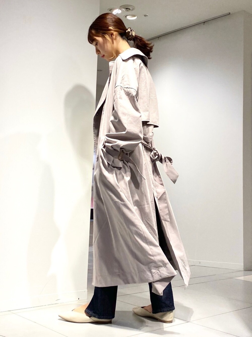 ブラウン系のトレンチコート、ブルー系のその他パンツ、ベージュ系のニット/セーターを着用したレディースの春コーディネートの1枚目の写真