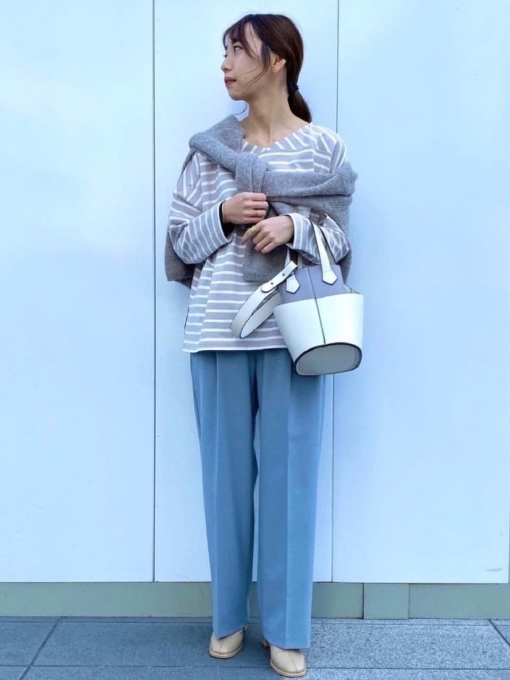 グレー系のニット/セーター、ベージュ系のTシャツ/カットソー、ホワイト系のトートバッグを着用したレディースの冬コーディネートの1枚目の写真