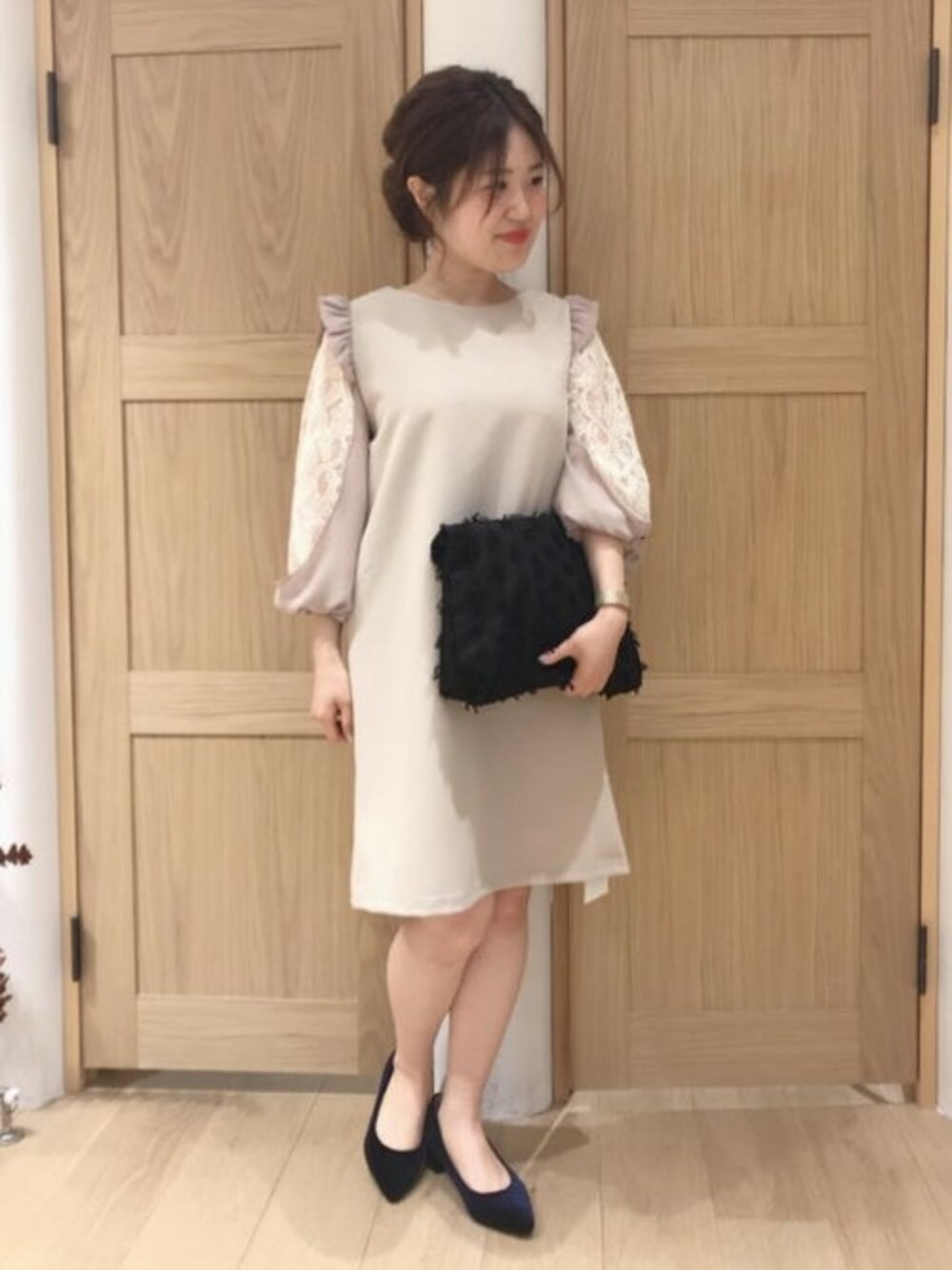 ベージュ系のワンピース、ブラック系のクラッチバッグ、ブルー系のパンプスを着用したレディースの春コーディネートの1枚目の写真