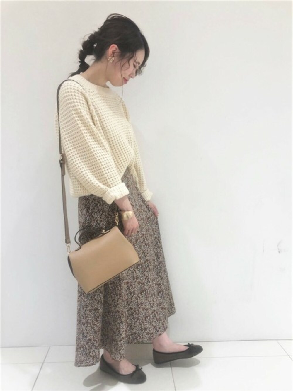 ホワイト系のニット/セーター、ブラウン系のスカート、ベージュ系のショルダーバッグを着用したレディースの秋コーディネートの1枚目の写真