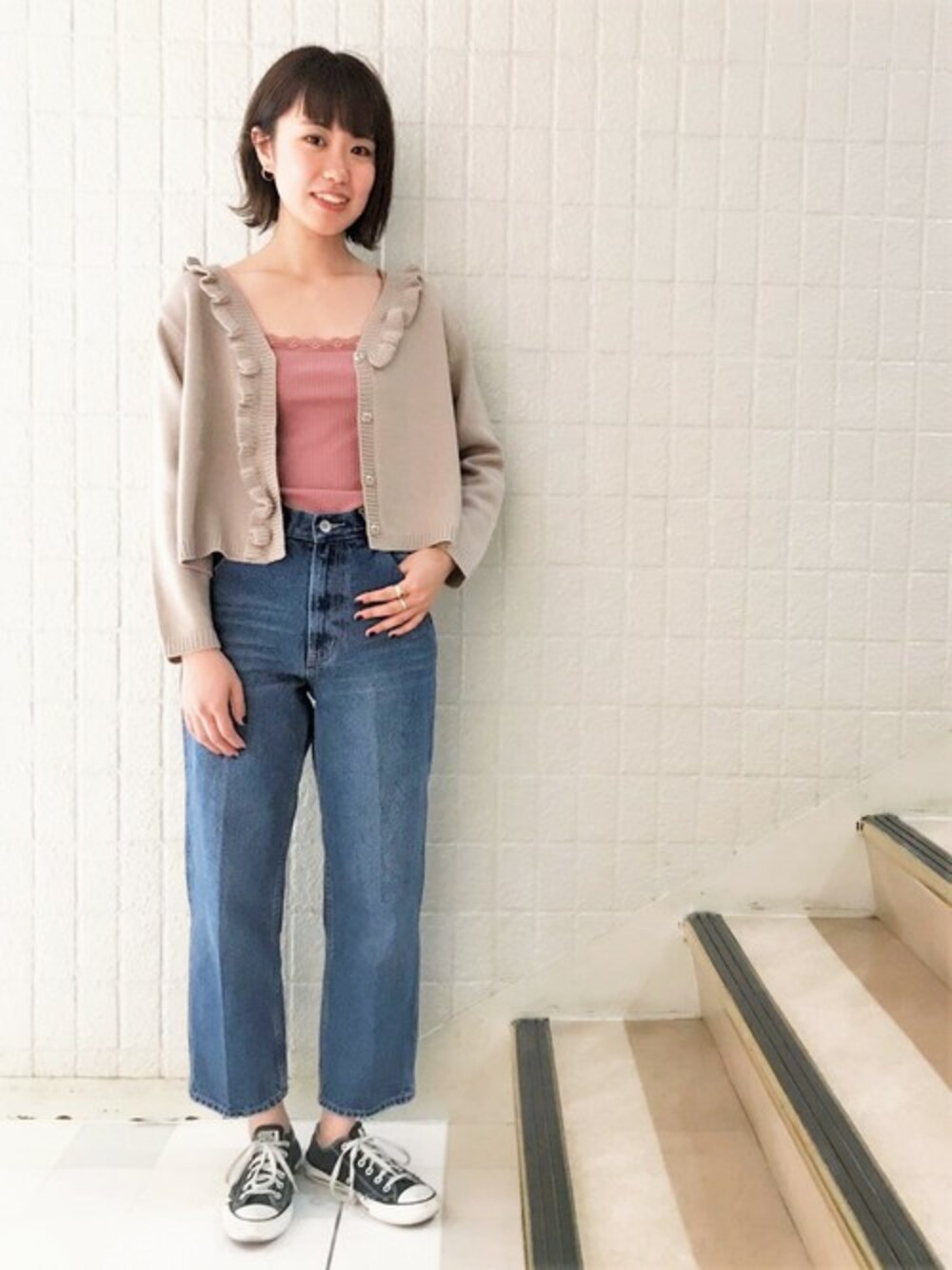 ベージュ系のカーディガン/ボレロ、ピンク系のキャミソール、ブルー系のデニムパンツを着用したレディースの秋コーディネートの1枚目の写真