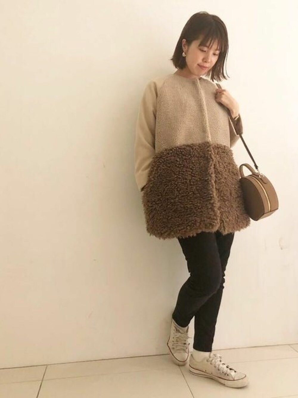 ブラウン系のムートンコート、ブラック系のデニムパンツ、ベージュ系のショルダーバッグを着用したレディースの秋コーディネートの1枚目の写真