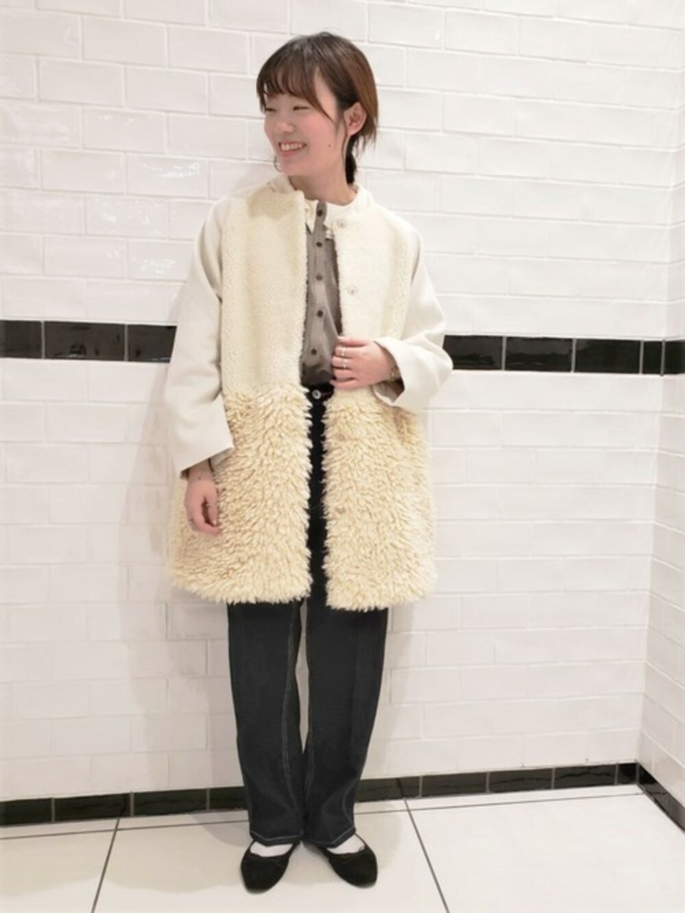 ホワイト系のムートンコート、ブラウン系のシャツ/ブラウス、ブルー系のデニムパンツを着用したレディースの秋コーディネートの1枚目の写真