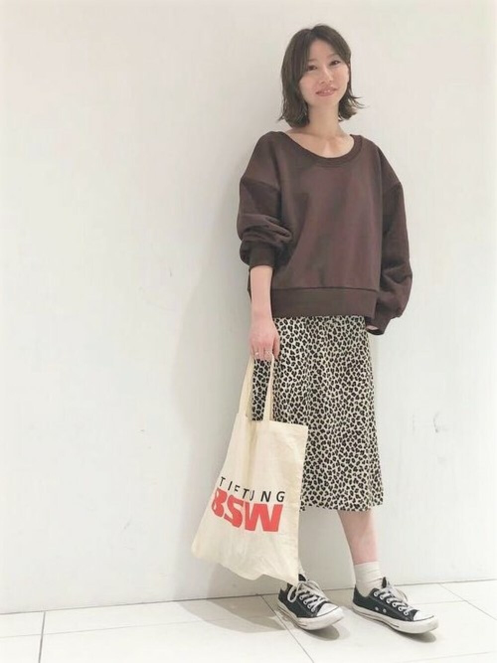 ブラウン系のスウェット、ホワイト系のスカートを着用したレディースの秋コーディネートの1枚目の写真