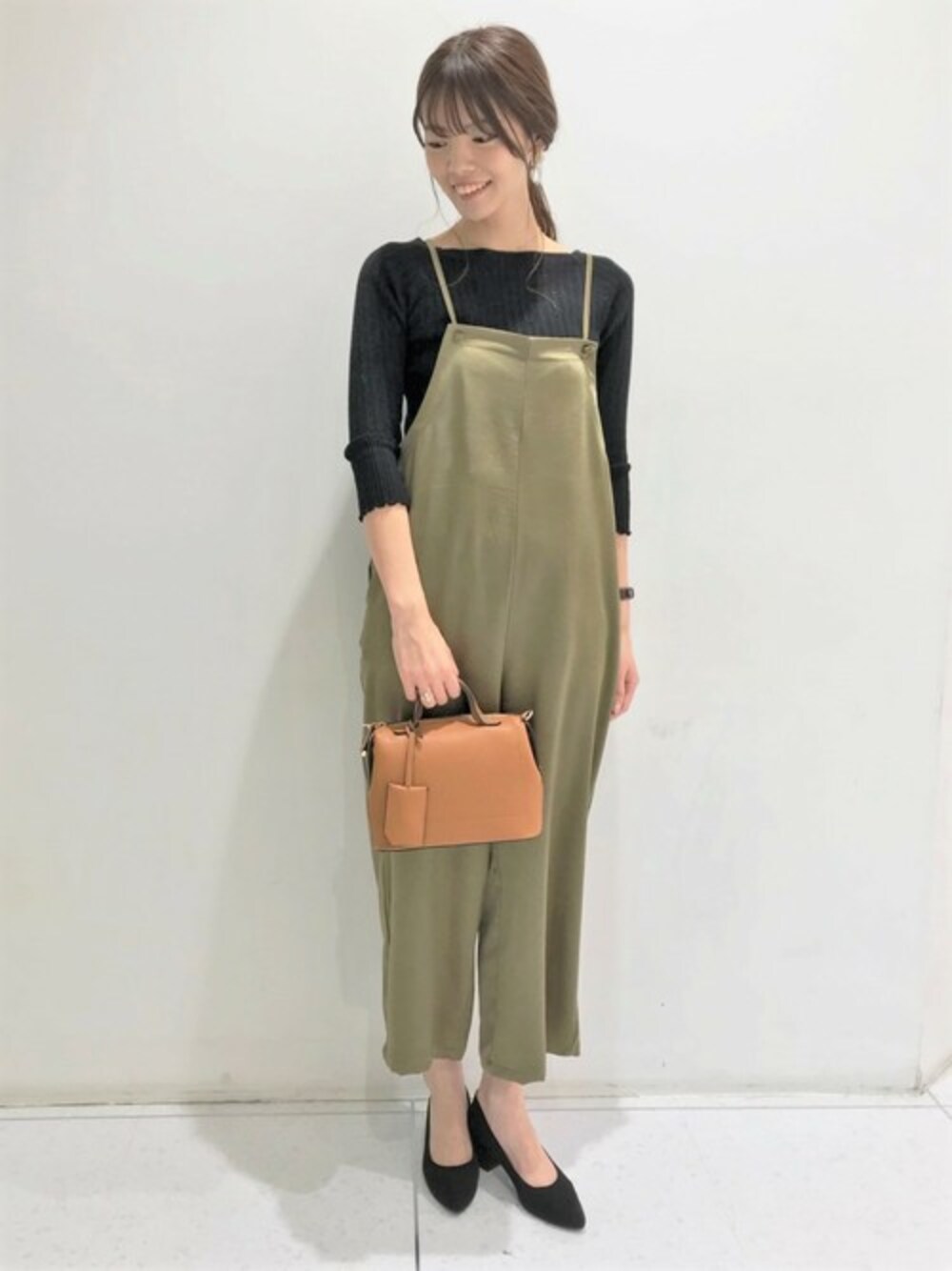 ブラック系のTシャツ/カットソー、グリーン系のジャンパースカート、ブラウン系のショルダーバッグを着用したレディースの秋コーディネートの1枚目の写真