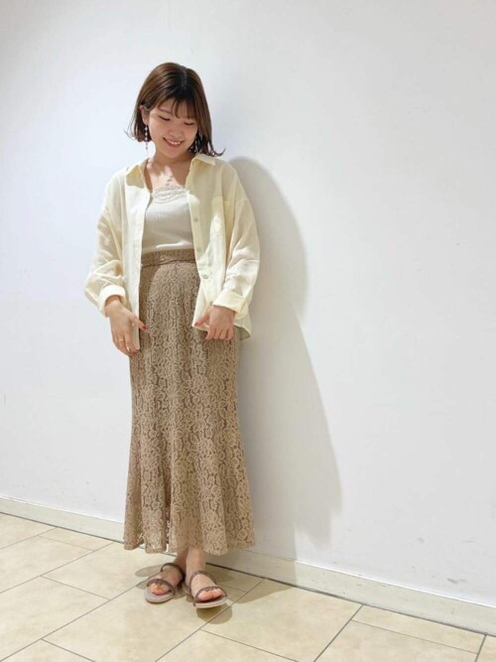 ベージュ系のスカート、ホワイト系のキャミソールを着用したレディースの夏コーディネートの1枚目の写真