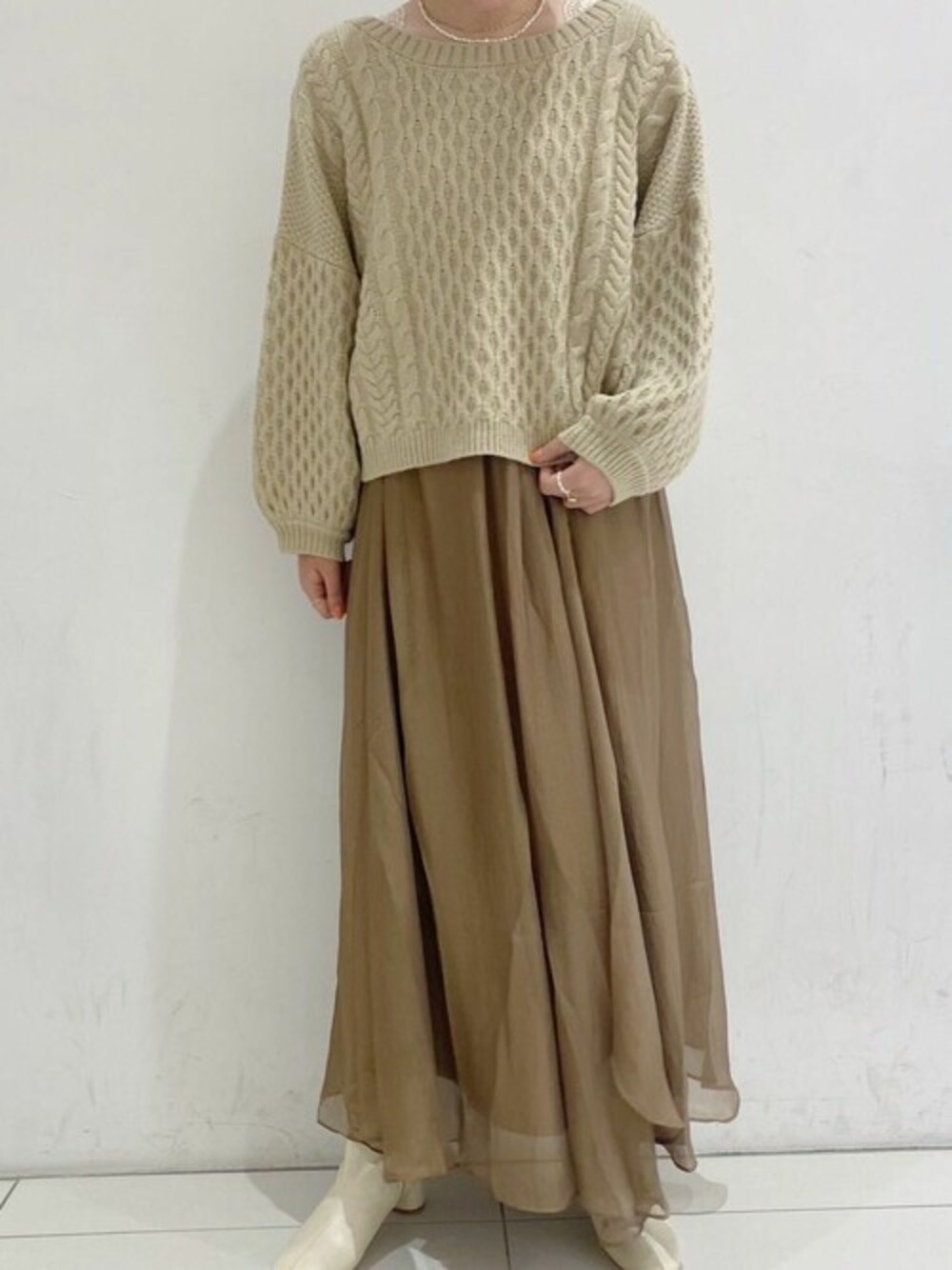 ベージュ系のニット/セーター、ブラウン系のスカートを着用したレディースの秋コーディネートの1枚目の写真