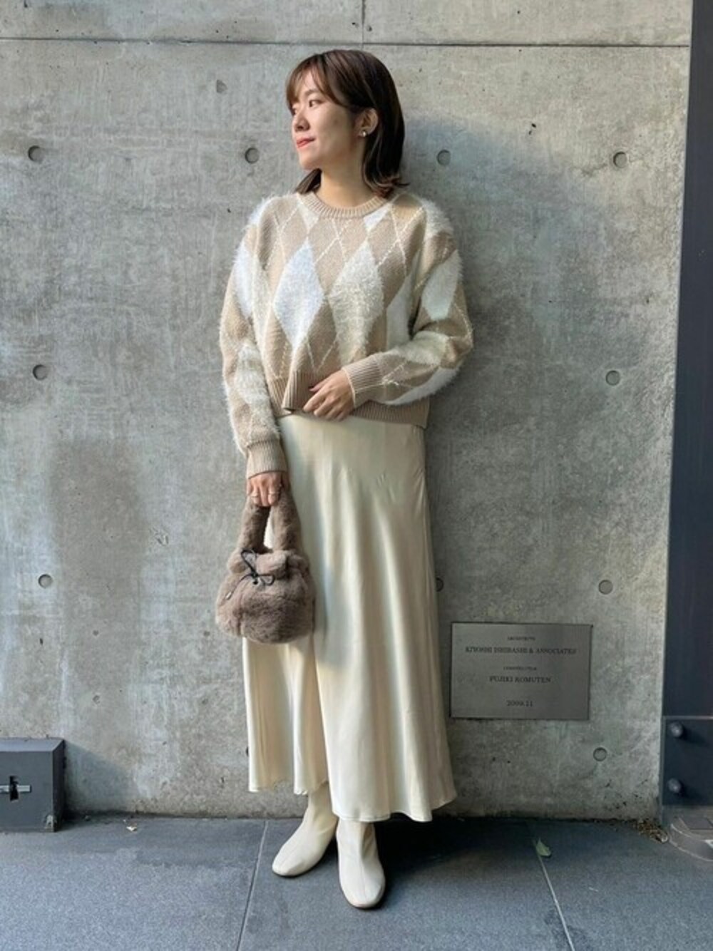 ベージュ系のニット/セーター、イエロー系のスカートを着用したレディースの秋コーディネートの1枚目の写真