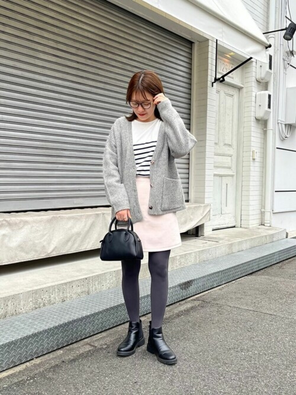 グレー系のスカート、グレー系のカーディガン/ボレロを着用したレディースの冬コーディネートの1枚目の写真