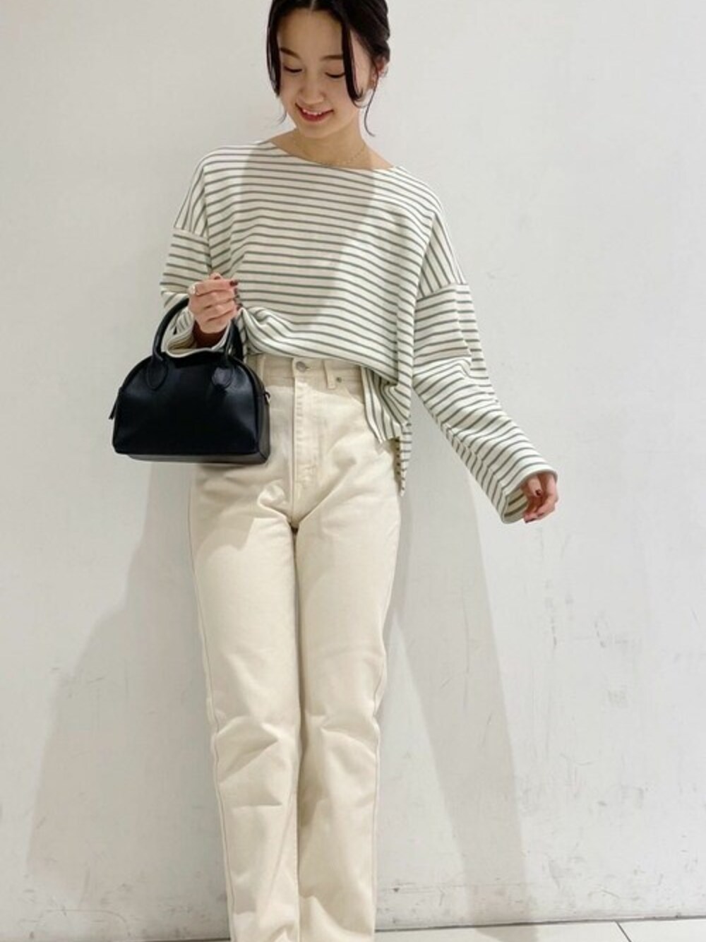 ホワイト系のデニムパンツ、グリーン系のTシャツ/カットソーを着用したレディースの冬コーディネートの1枚目の写真