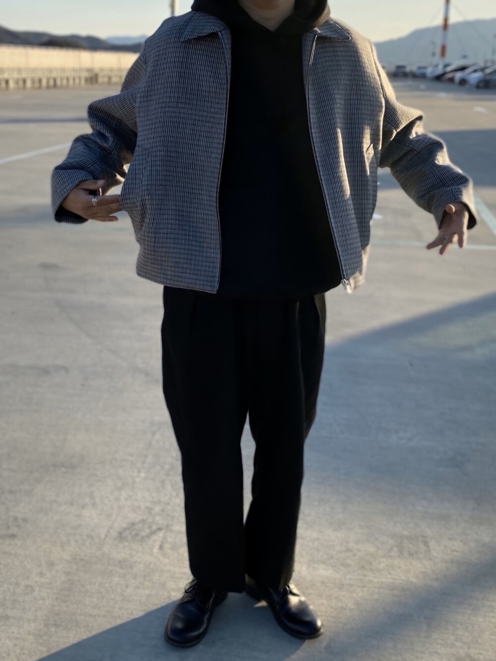 グレー系のブルゾン、ブラック系のパーカー、ブラック系のスラックスを着用したメンズの冬コーディネートの1枚目の写真