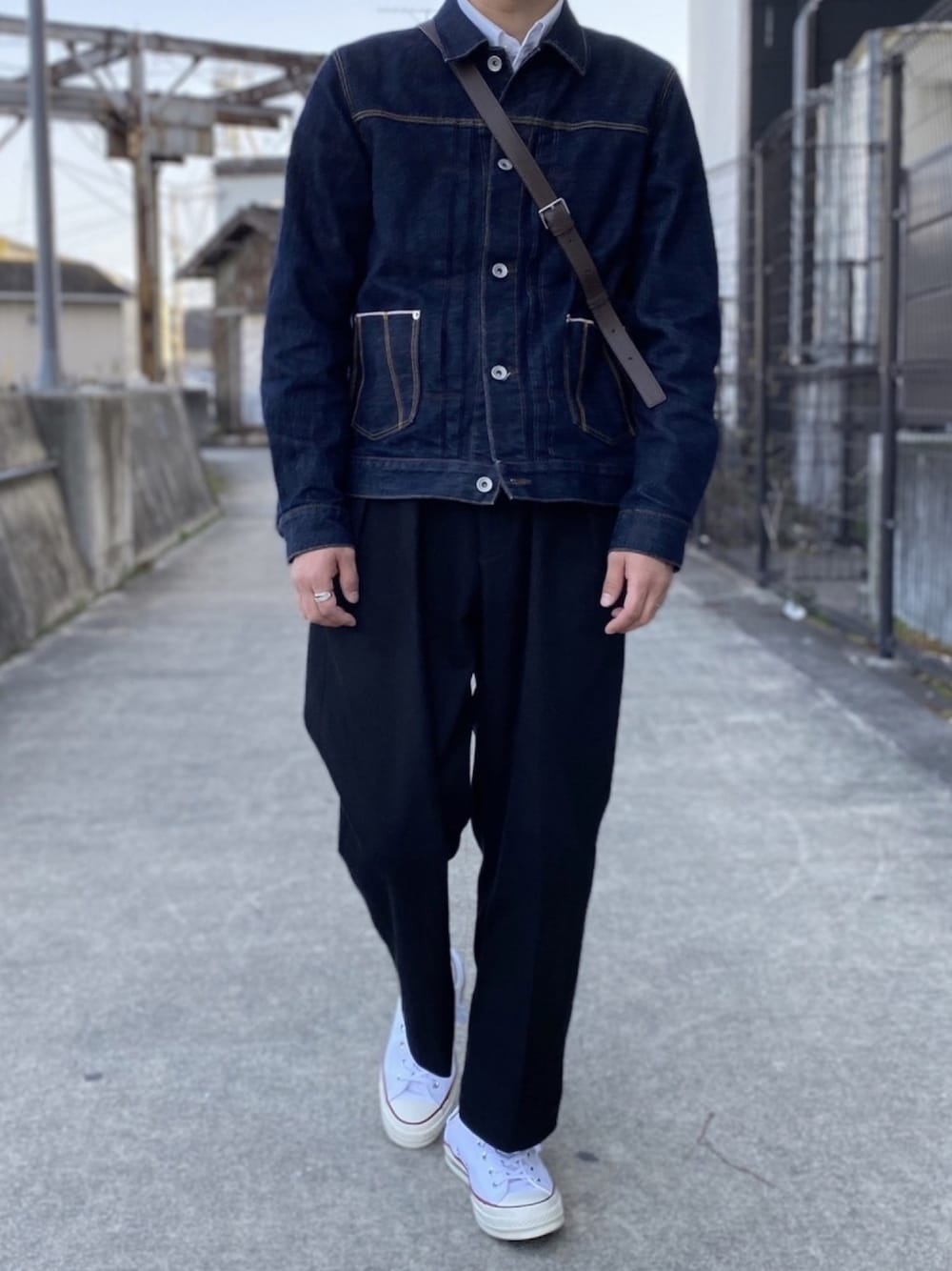 ブラック系のスラックス、ブラウン系のショルダーバッグ、ホワイト系のシャツ/ブラウスを着用したメンズの春コーディネートの1枚目の写真