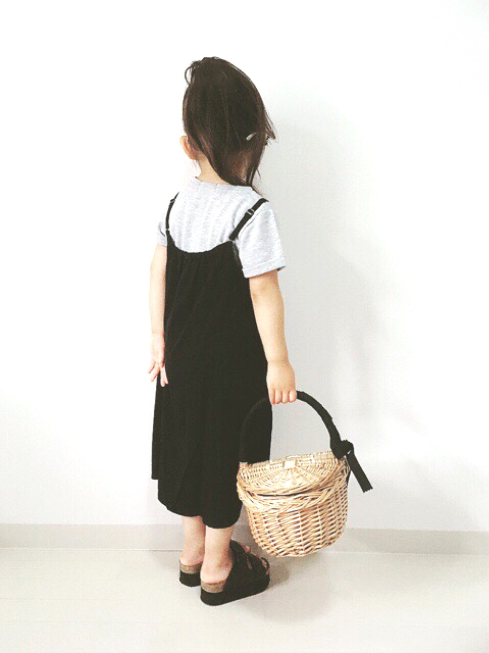 ブラック系のワンピース、レッド系のかごバッグ、ブラック系のサンダルを着用したキッズの夏コーディネートの1枚目の写真