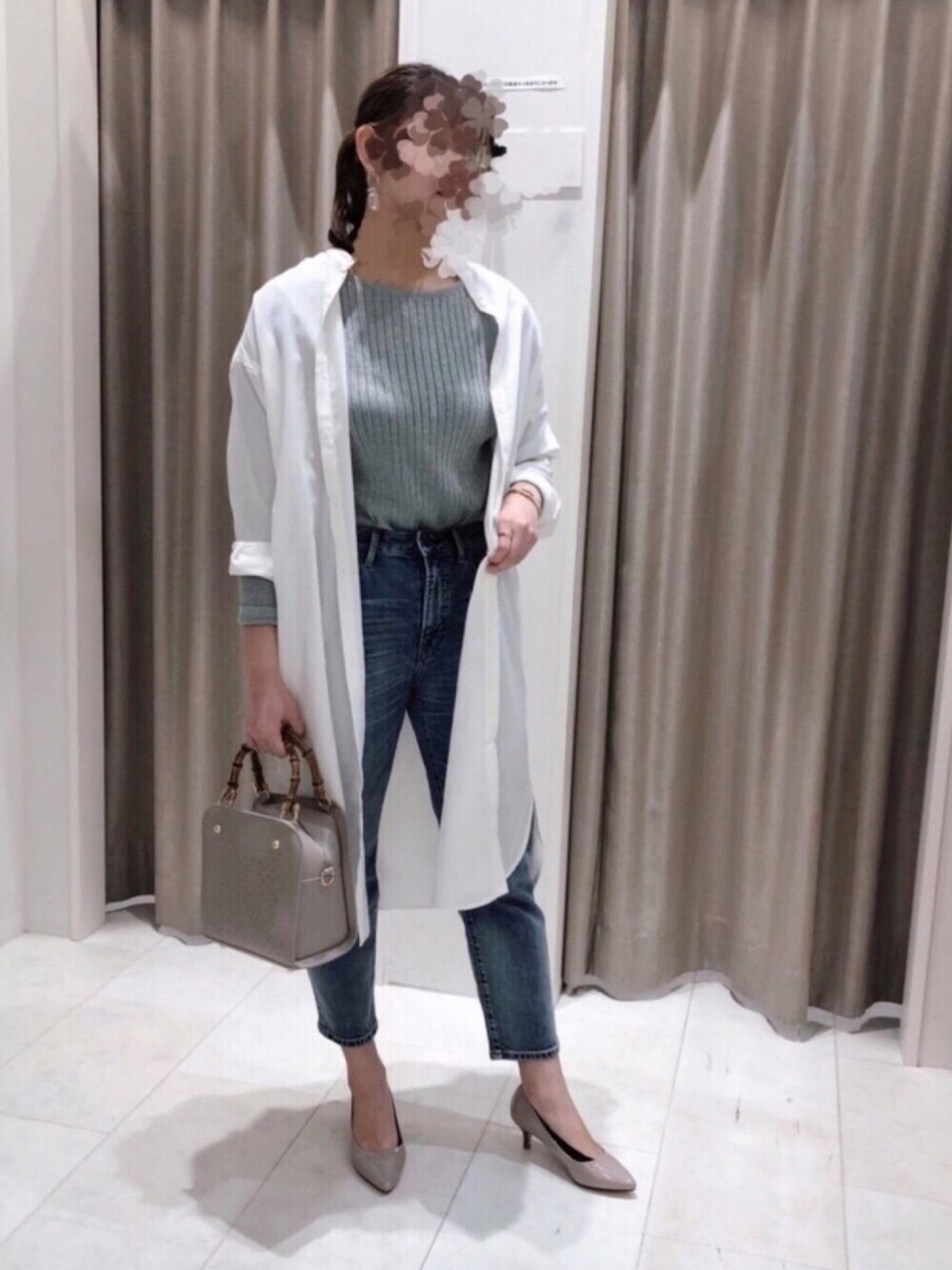 グリーン系のニット/セーター、ホワイト系のワンピース、ブルー系のデニムパンツを着用したレディースの春コーディネートの1枚目の写真