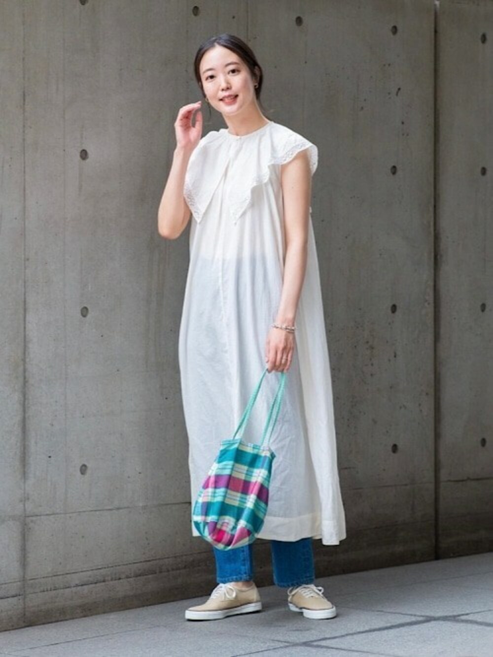 グリーン系のトートバッグ、ブルー系のデニムパンツ、ホワイト系のワンピースを着用したレディースの春コーディネートの1枚目の写真