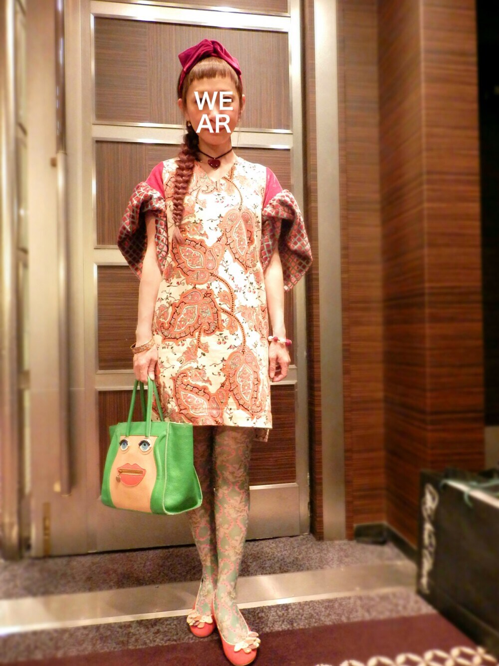 ベージュ系のワンピース、グリーン系のハンドバッグ、ブルー系のノーカラージャケットを着用したレディースの冬コーディネートの1枚目の写真