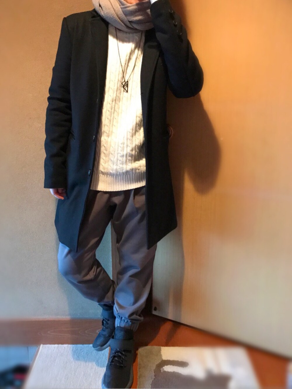 ブラック系のチェスターコート、ホワイト系のニット/セーター、グレー系のその他パンツを着用したメンズの春コーディネートの1枚目の写真