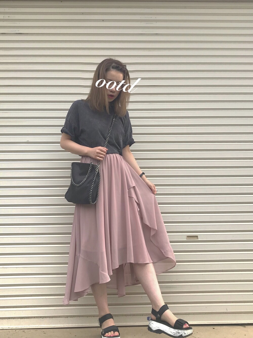 ブラック系のショルダーバッグ、ブラック系のサンダル、ピンク系のスカートを着用したレディースの夏コーディネートの1枚目の写真