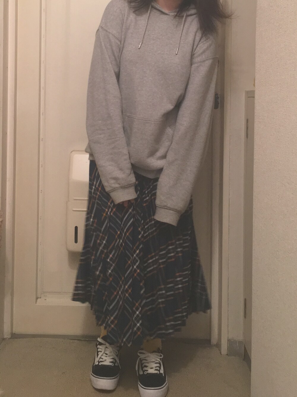 グレー系のパーカー、グリーン系のスカート、ブラック系のスニーカーを着用したレディースの秋コーディネートの1枚目の写真